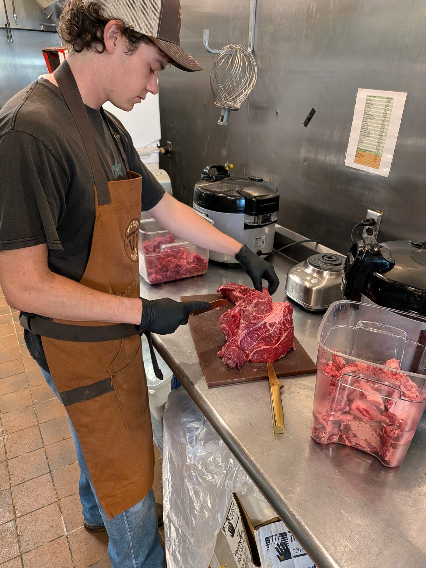 A Victor Tango cook hand-trimming a whole cut of beef in the kitchen